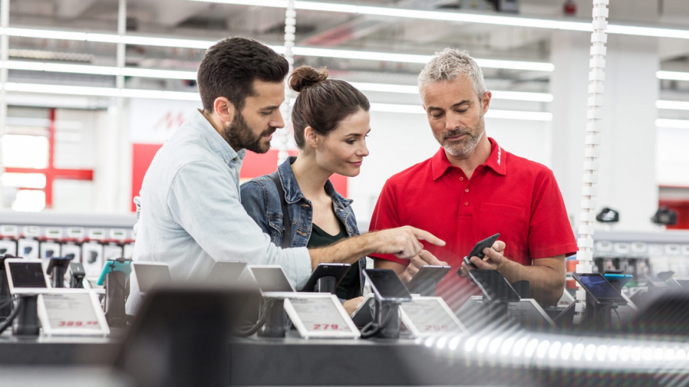 MediaMarkt salesman shows usage of smartphone to customers