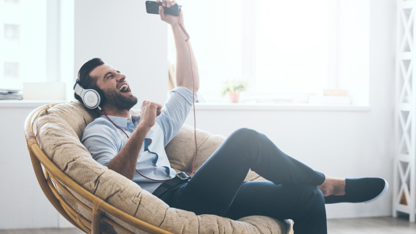 Mann sitzt lässig auf Sessel, hört Musik und singt laut mit